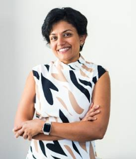 A person smiling with arms crossed Description automatically generated